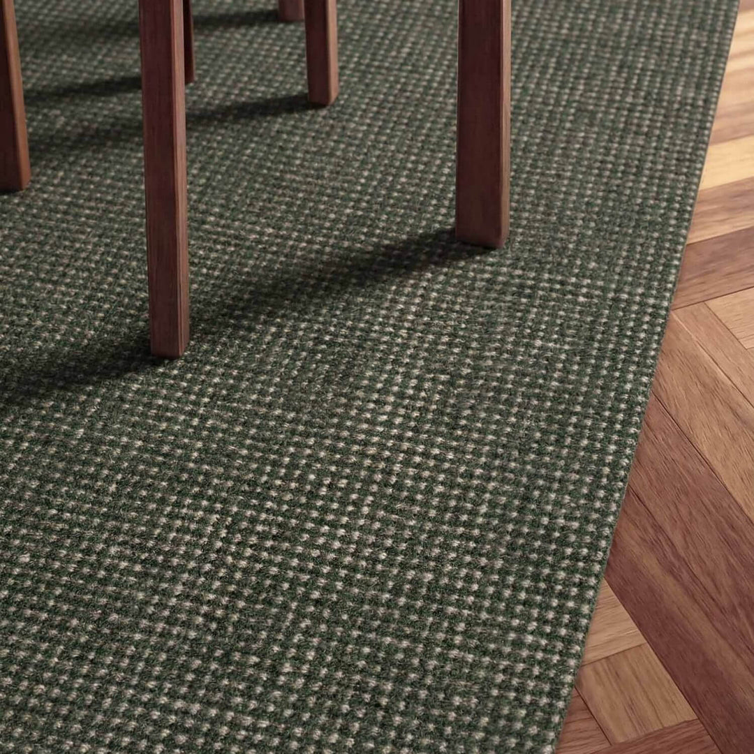 Green textured carpet with wooden floor and chair legs