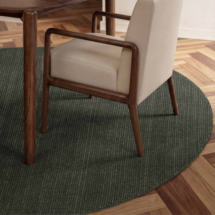 Chair with wooden frame and beige cushion on a green round rug in a room with wooden flooring.