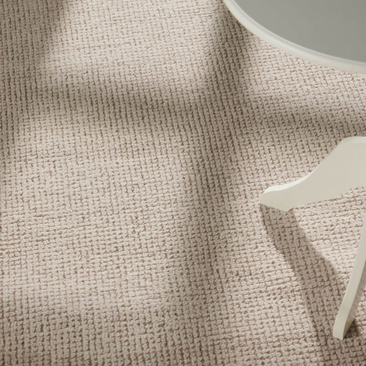 Textured beige fabric with a small white decorative item on a neutral background
