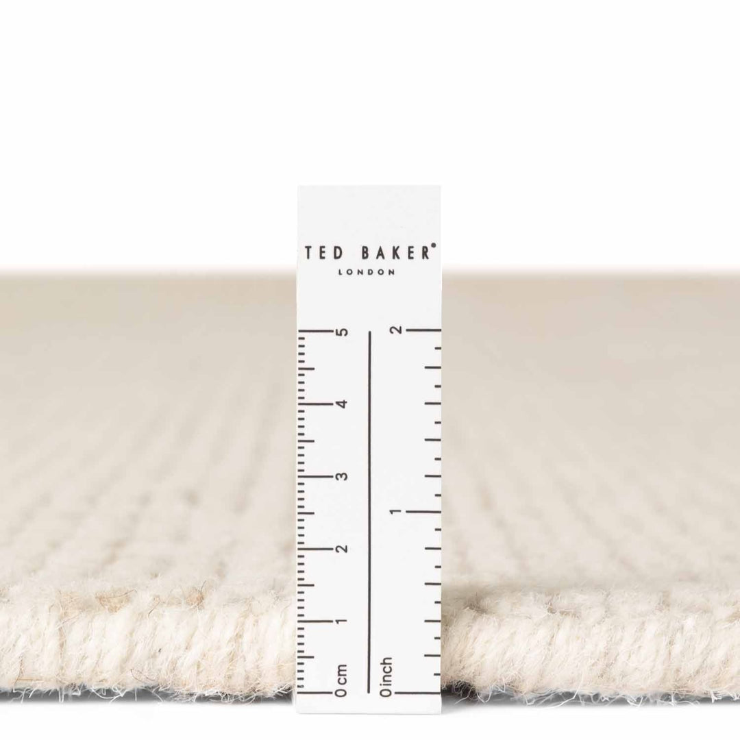 Close-up of a textured fabric with a ruler and 'Ted Baker London' label.