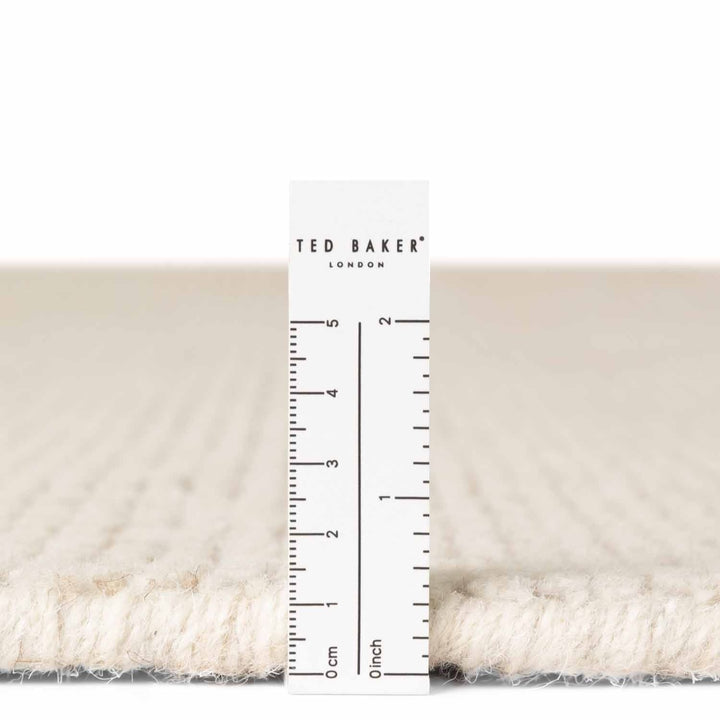 Close-up of a textured fabric with a ruler and 'Ted Baker London' label.