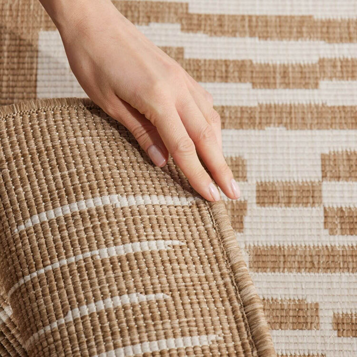 Hand touching a woven mat with a geometric pattern