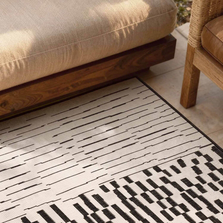 Patterned rug on a wooden floor with furniture in the background