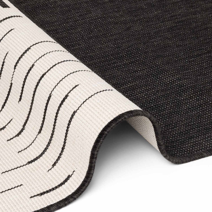 Close-up of a black and white textured rug corner.