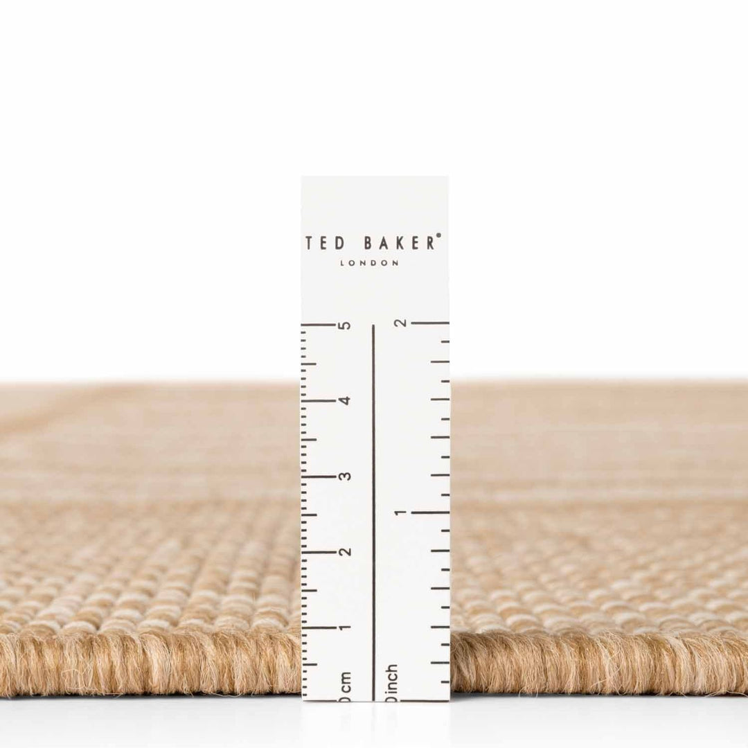 Beige woven mat with a ruler and 'Ted Baker' branding on a white background