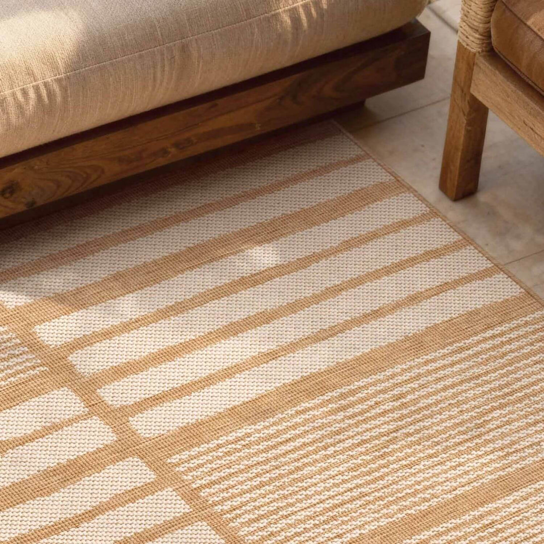 Close-up of a beige and white striped rug with wooden furniture in the background
