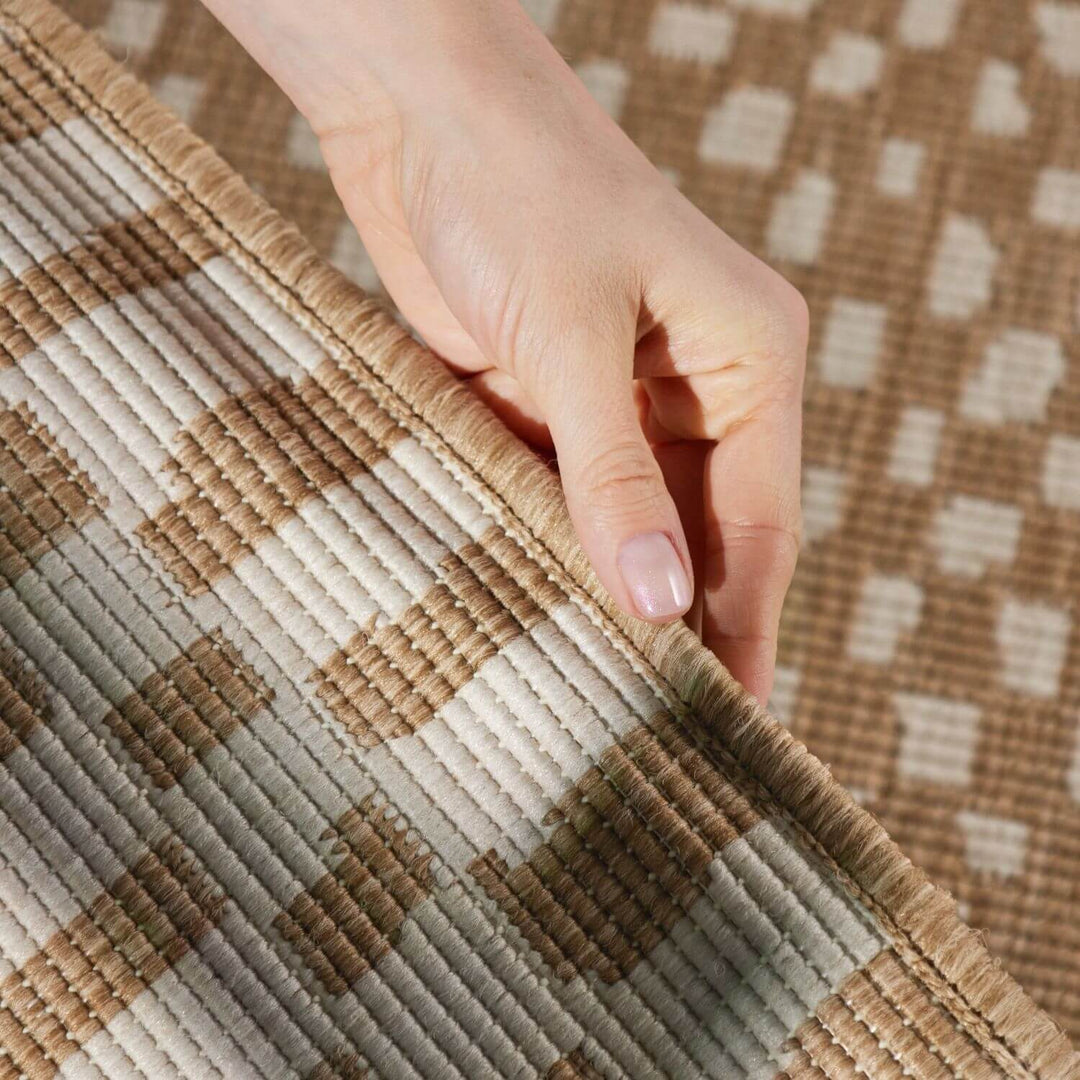 Hand touching a textured brown and beige checkered fabric