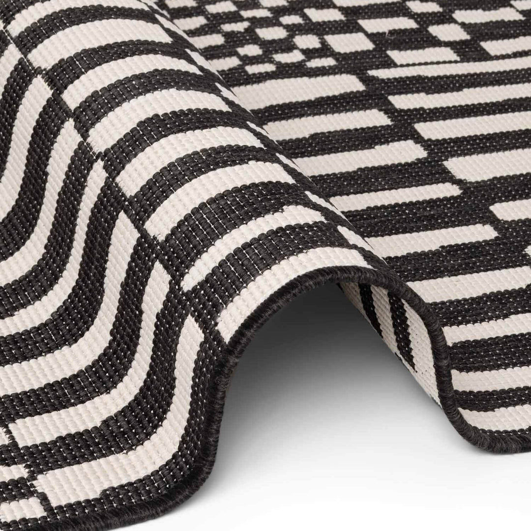 Close-up of a black and white striped rug on a light gray background