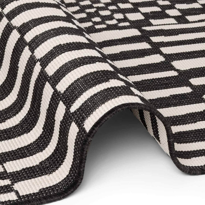Close-up of a black and white striped rug on a light gray background
