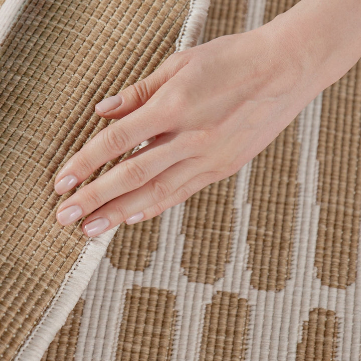 Hand touching a textured brown and beige woven fabric
