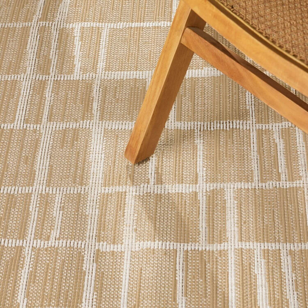 Close-up of a textured beige and white checkered floor with a wooden chair leg.