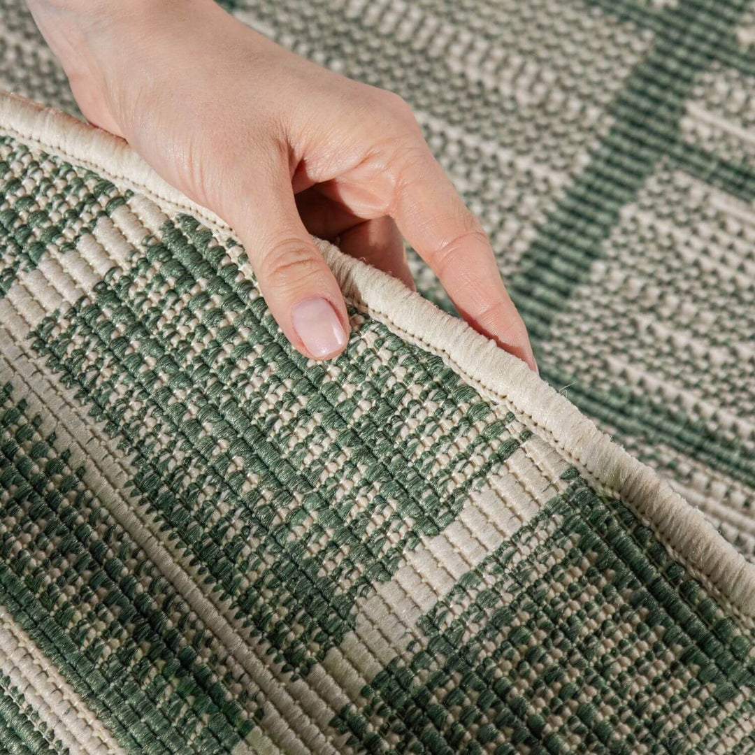 Hand touching a green and beige checkered patterned rug