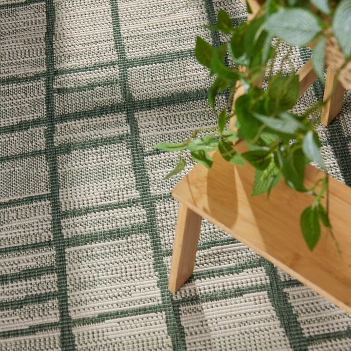 Wooden plant stand with a plant on a green and white checkered rug