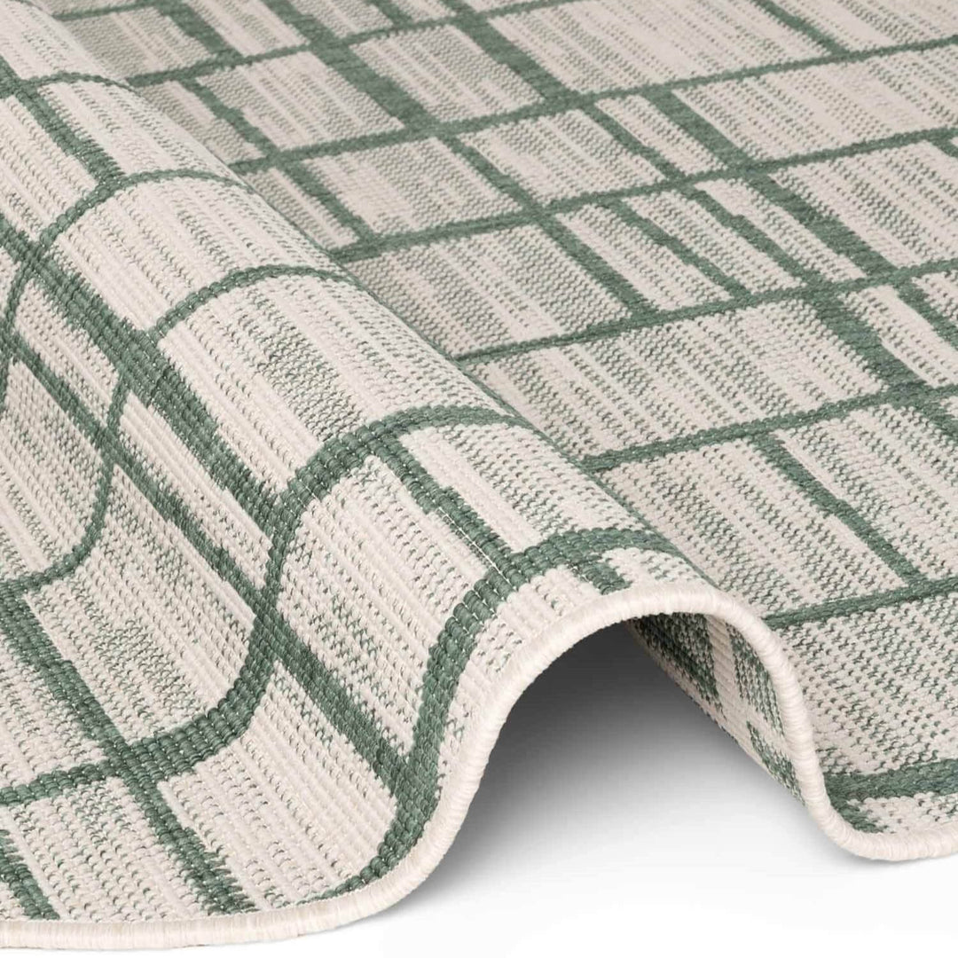 Close-up of a green and beige checkered rug on a white background