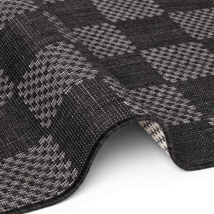 Close-up of a textured black and gray checkered fabric with a white background