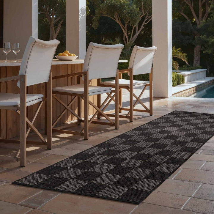Outdoor patio setting with wooden chairs and a checkered rug.
