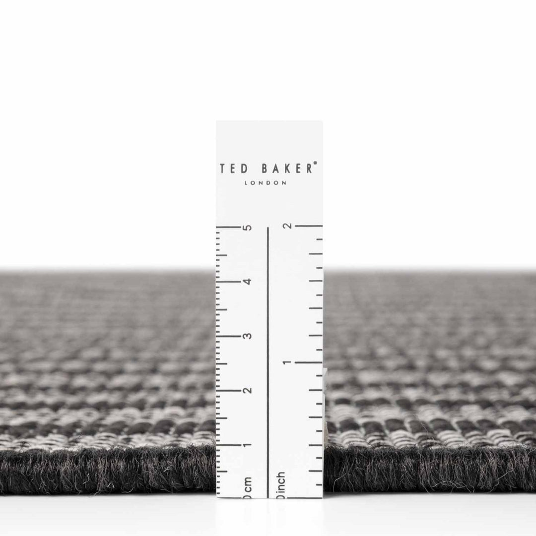 Gray textured rug with a ruler and 'Ted Baker' branding on a white background