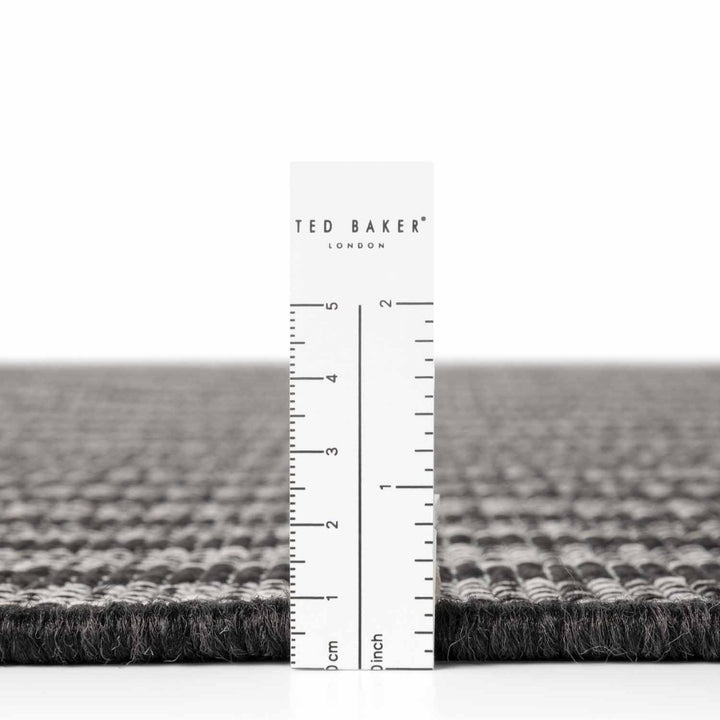Gray textured rug with a ruler and 'Ted Baker' branding on a white background