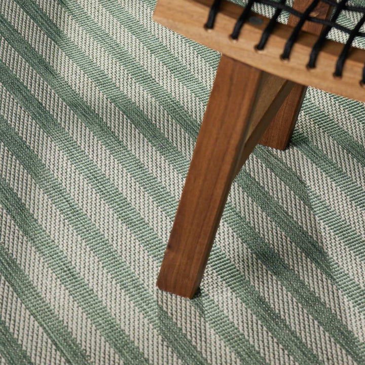 Wooden comb on a green and gray striped fabric background
