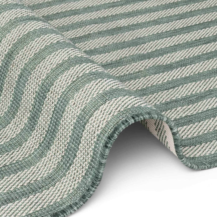 Close-up of a green and white striped fabric roll on a white background