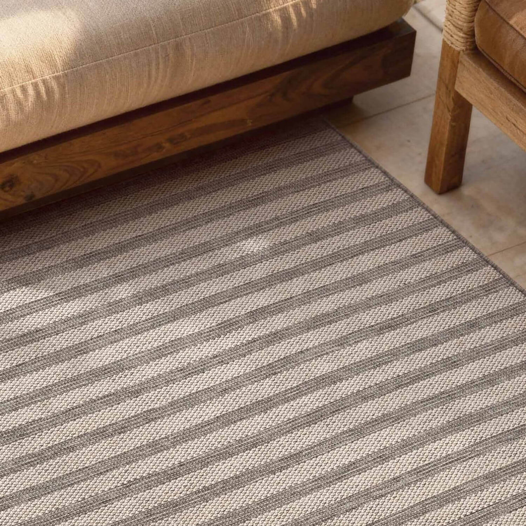 Striped rug with a sofa and wooden furniture in the background