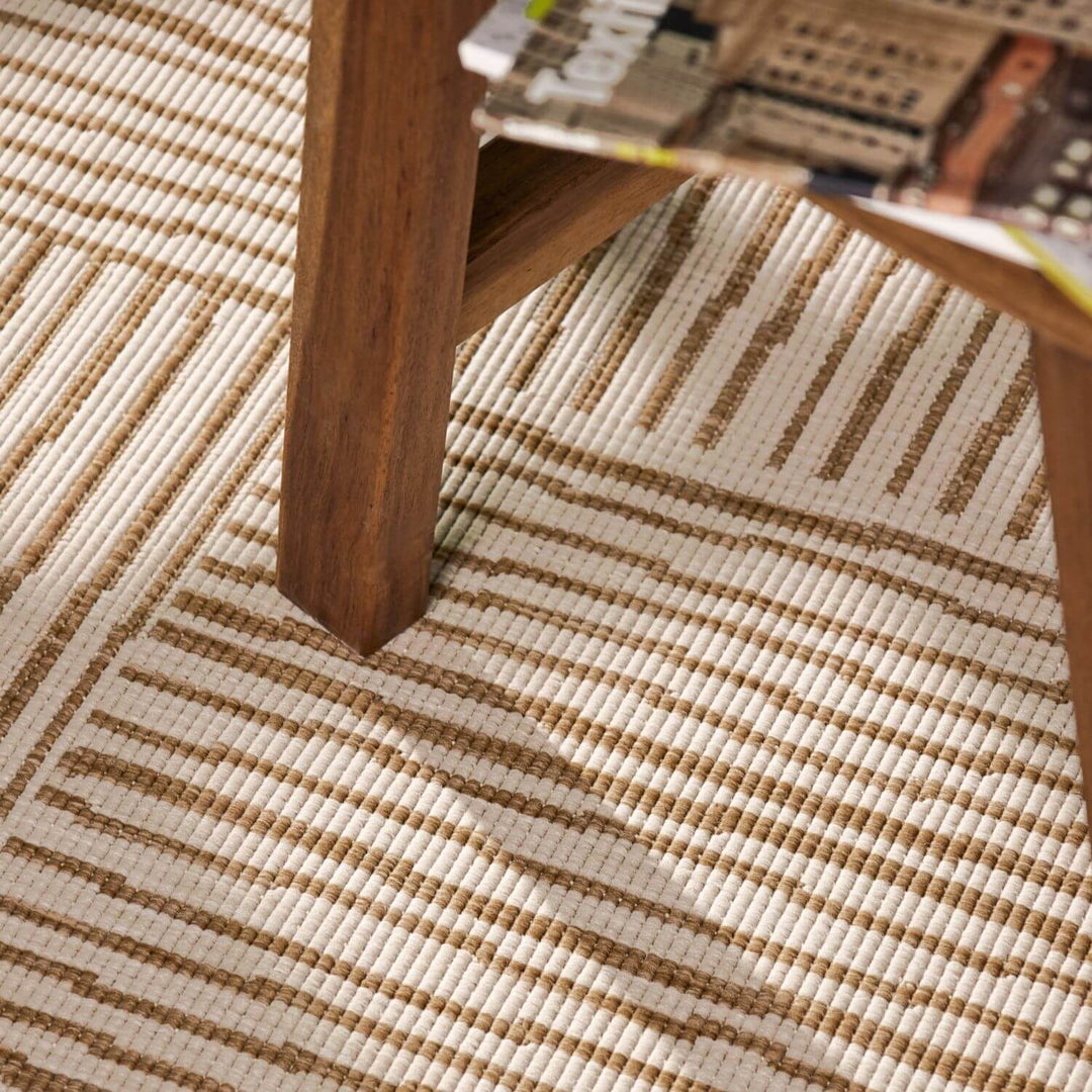 Close-up of a wooden table leg on a textured beige and brown rug.