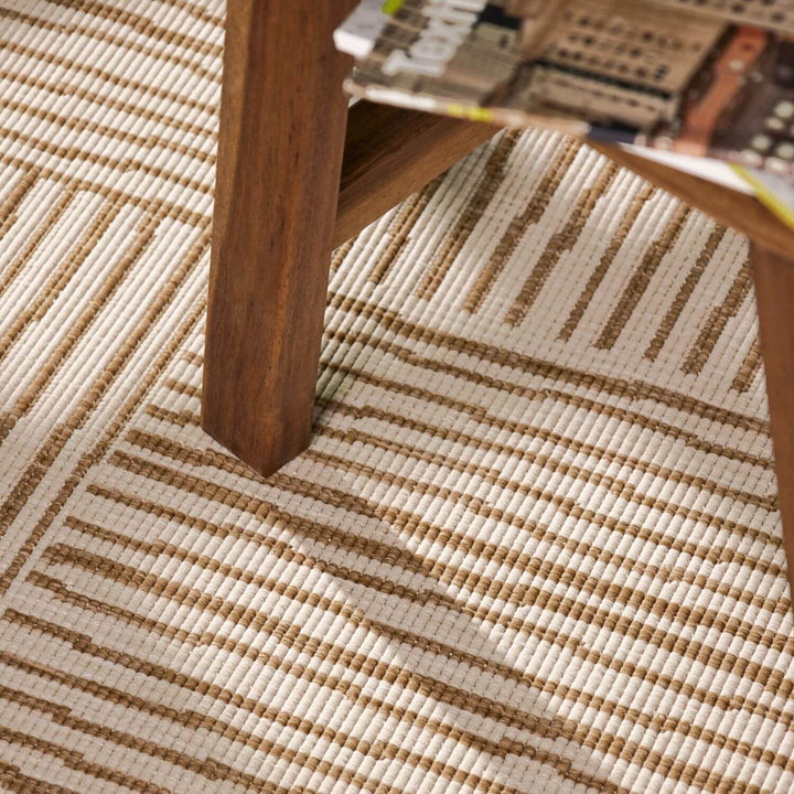 Close-up of a wooden table leg on a textured beige and brown rug.