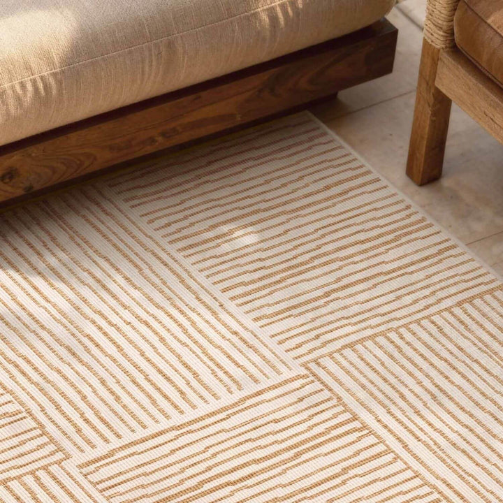 Beige patterned rug on a wooden floor with a sofa and chair in the background.