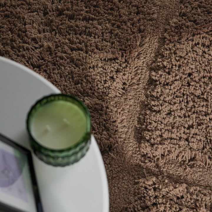 Green candle on a white plate with a brown textured surface