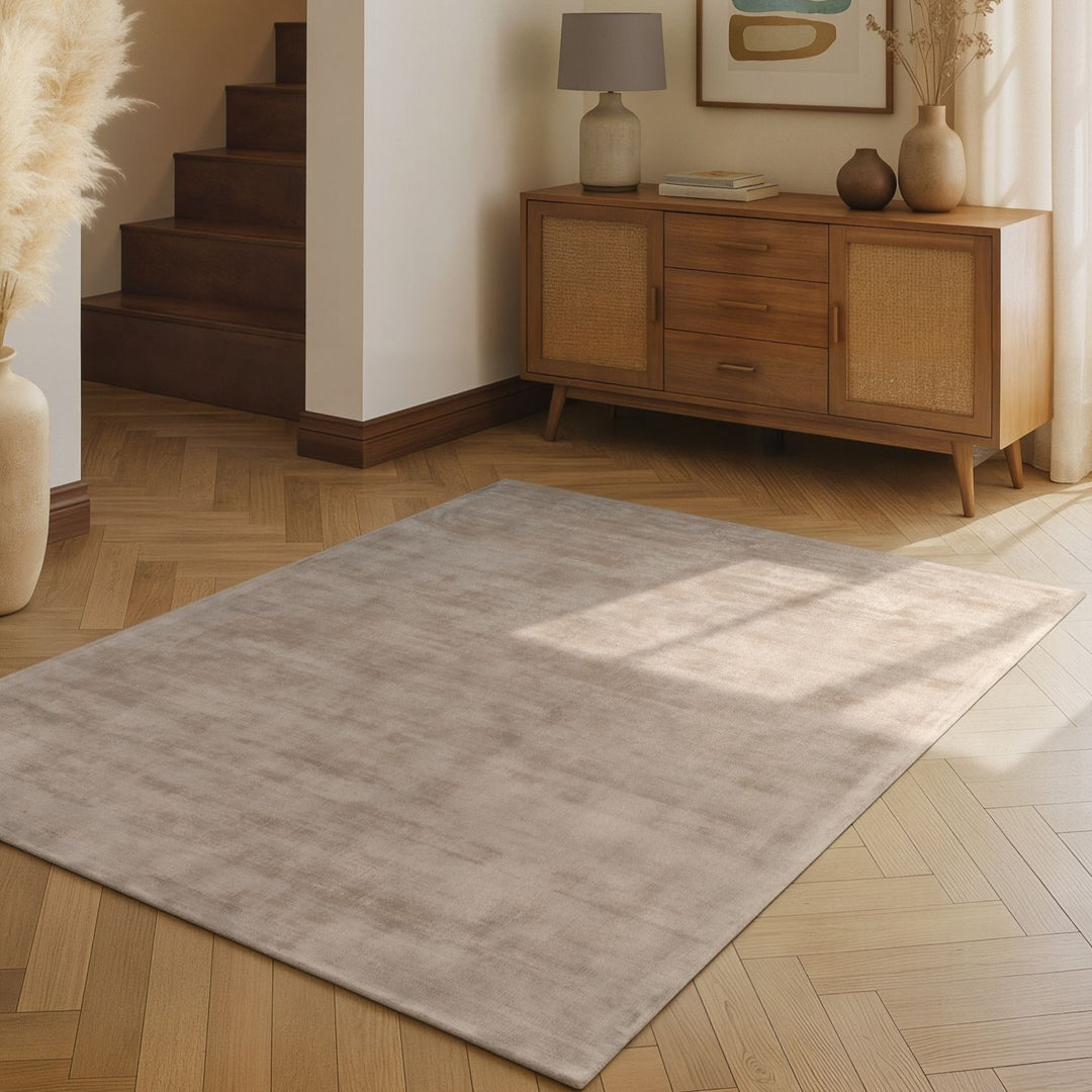 Light gray rug on a wooden floor with a wooden sideboard in the background.
