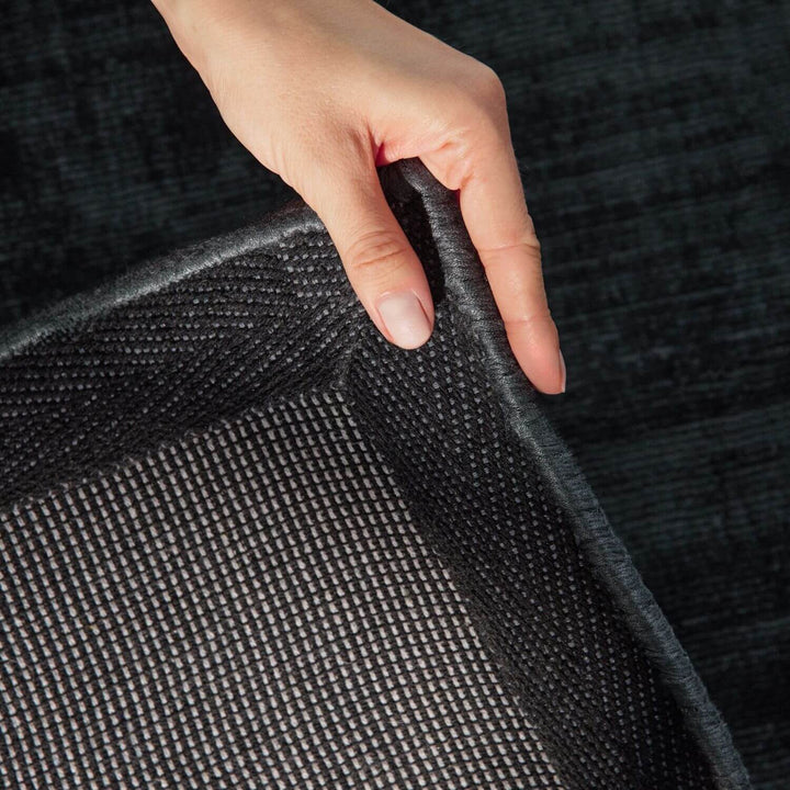 Hand touching a textured black fabric surface