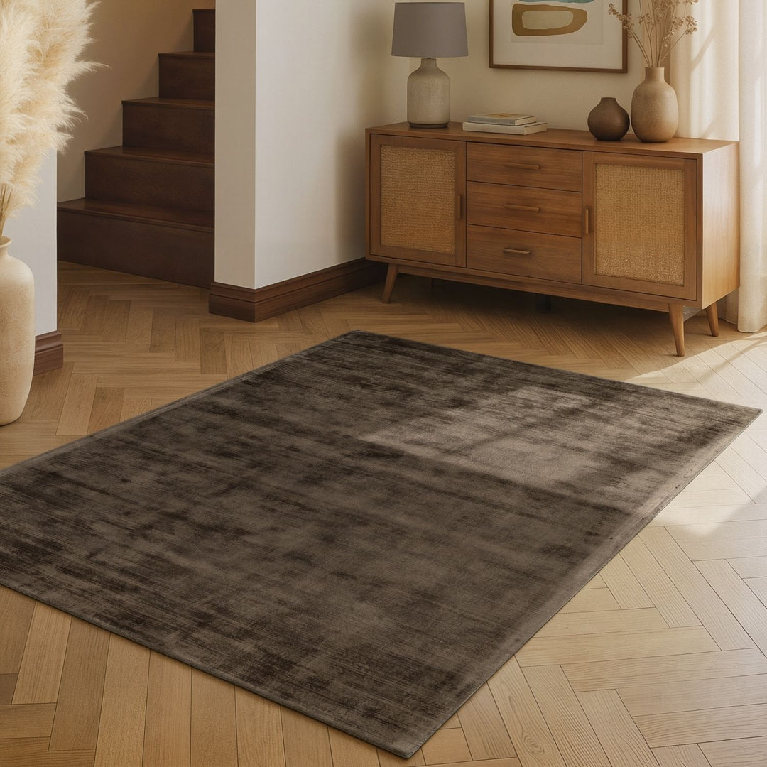 Gray rug on a wooden floor with a wooden sideboard in the background
