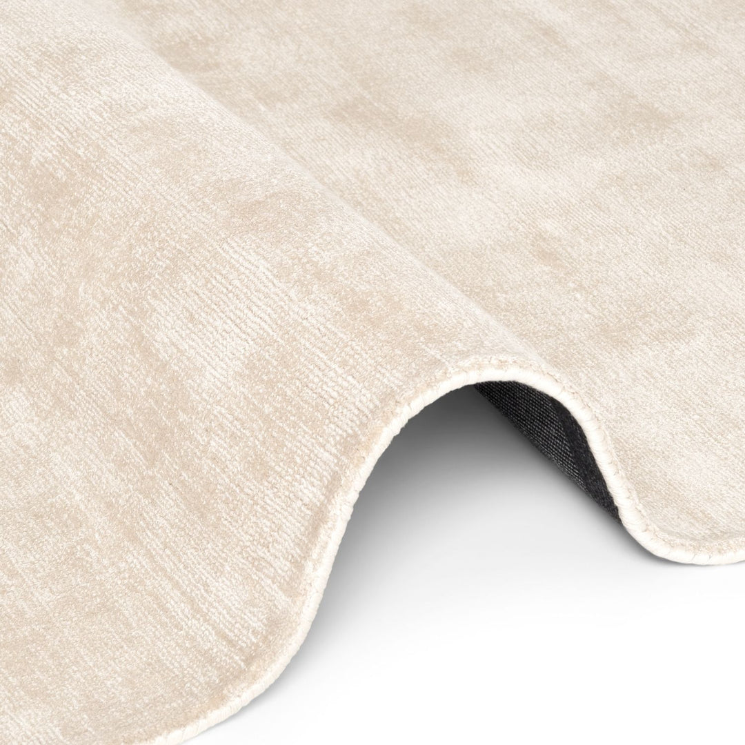 Close-up of a beige textured rug corner on a white background