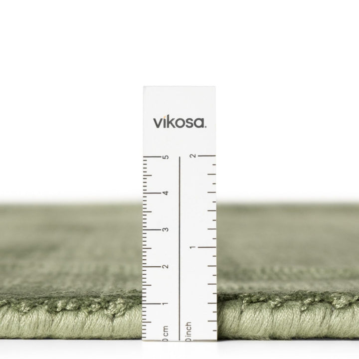 Green rug with a ruler and 'vikosa' branding on a white background