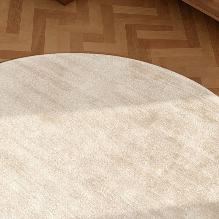 Round beige rug on a wooden floor