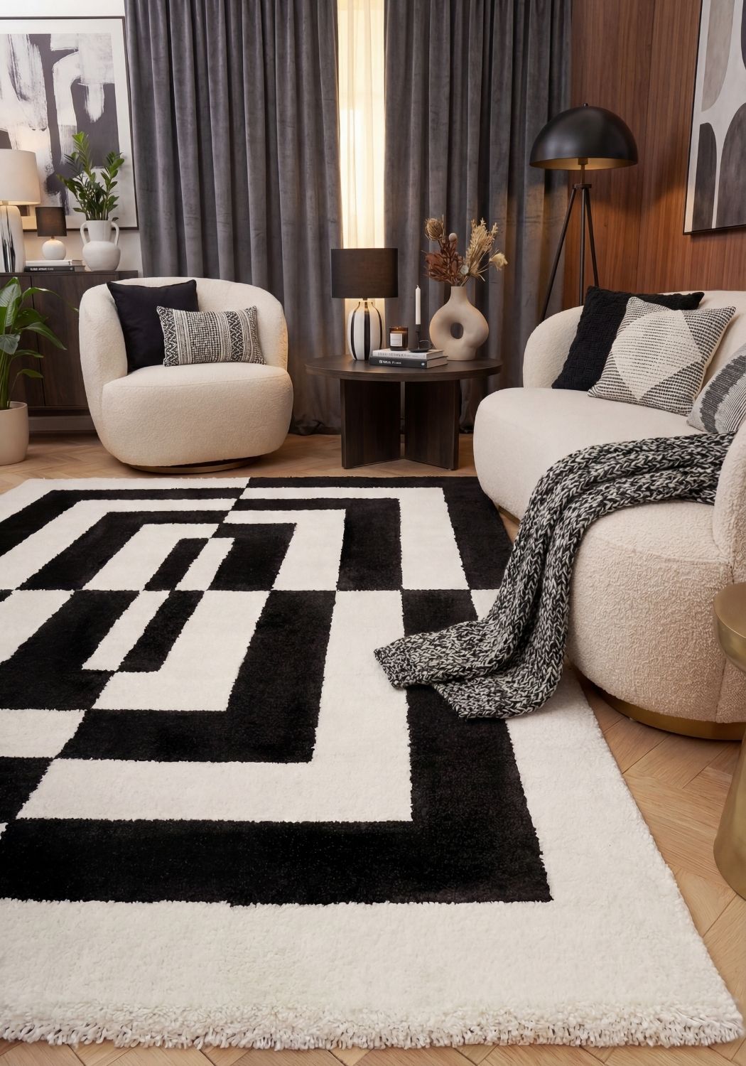 Modern living room with a black and white geometric rug, white armchair, and decorative pillows.