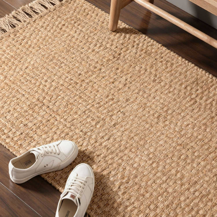White sneakers on a textured beige rug with wooden furniture.