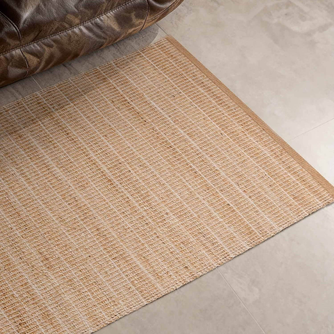 Textured beige rug on a tiled floor with a brown leather chair corner.