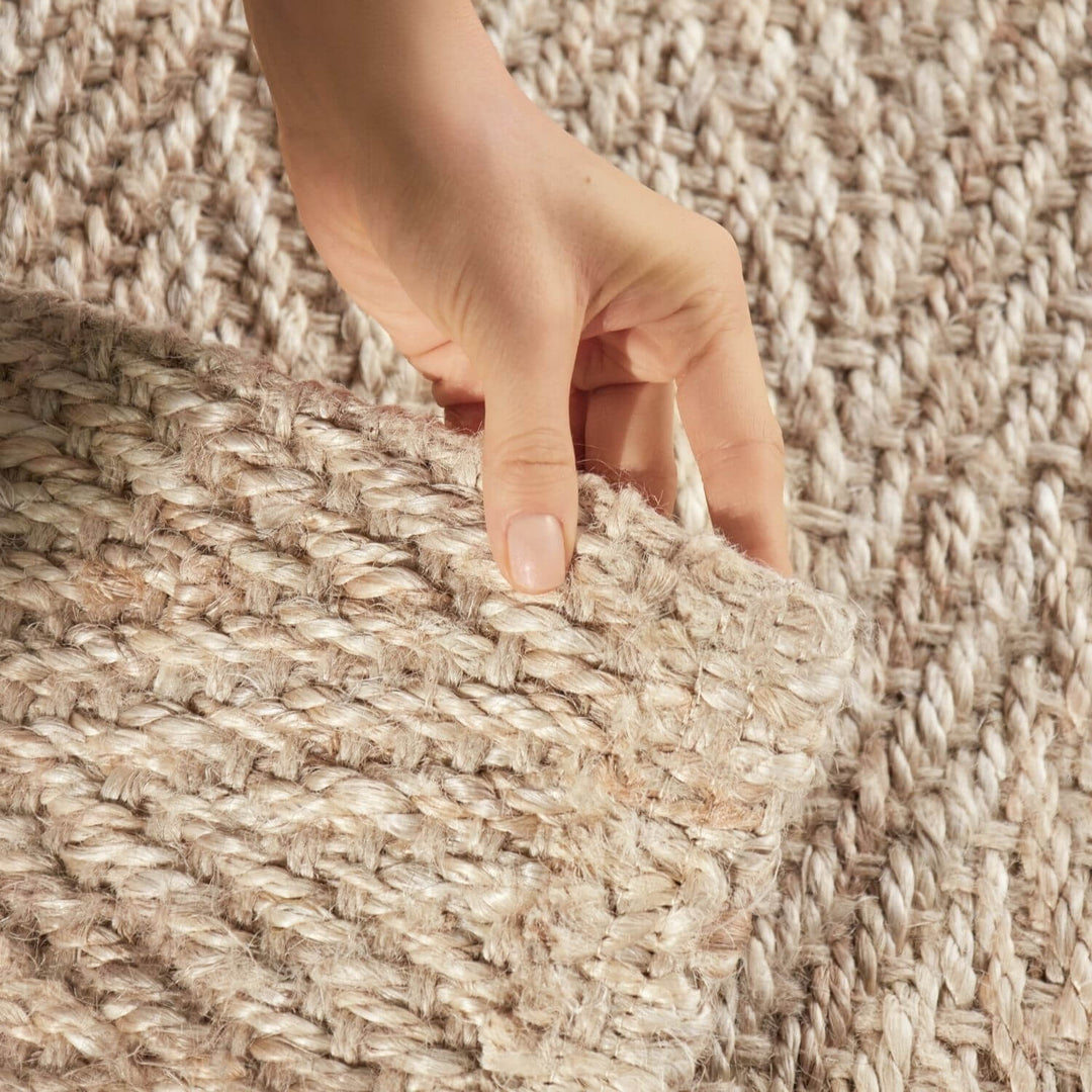 Hand touching a textured beige carpet