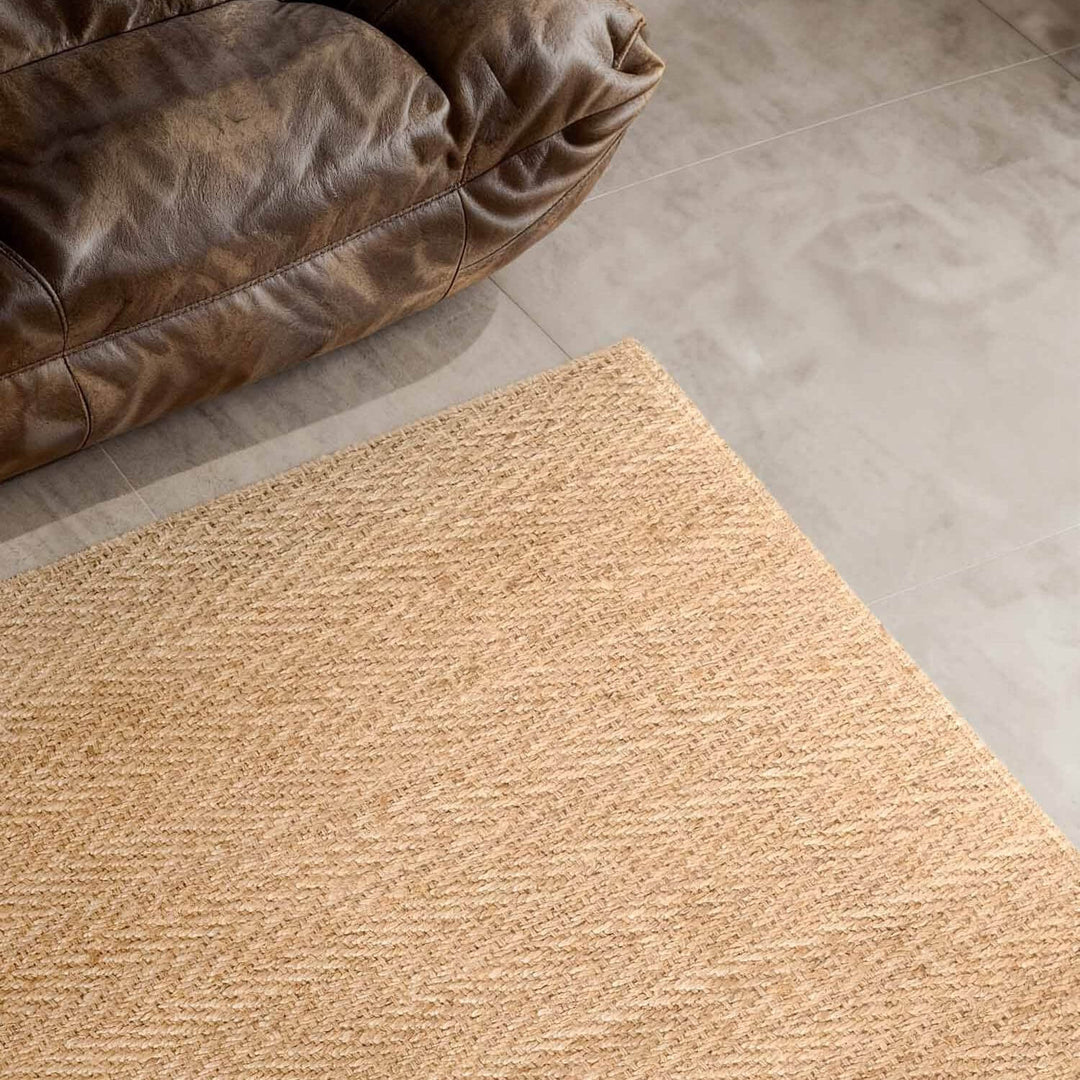 Beige rug on a tiled floor next to a brown leather chair.