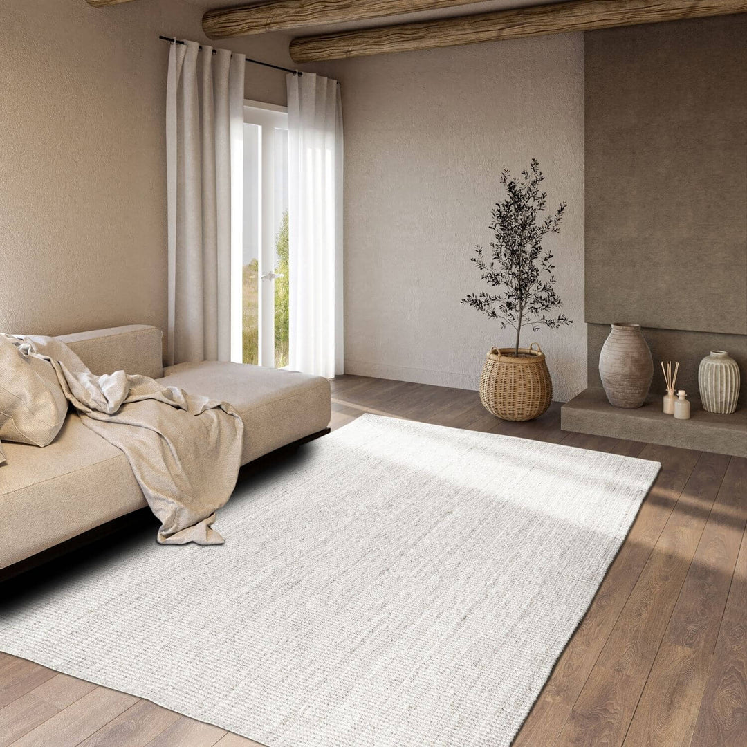 Modern living room with a beige sofa, white rug, and decorative elements.