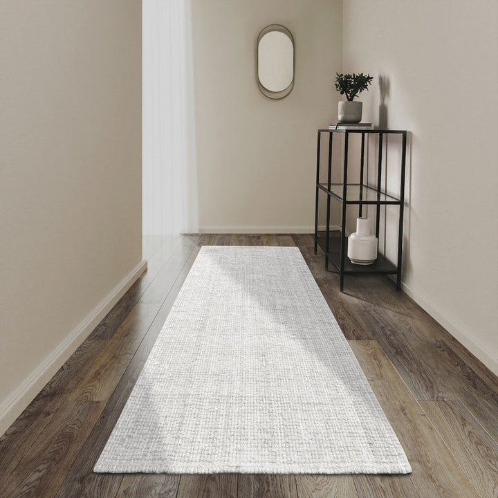 White runner rug on a wooden floor with a side table and mirror in the background.