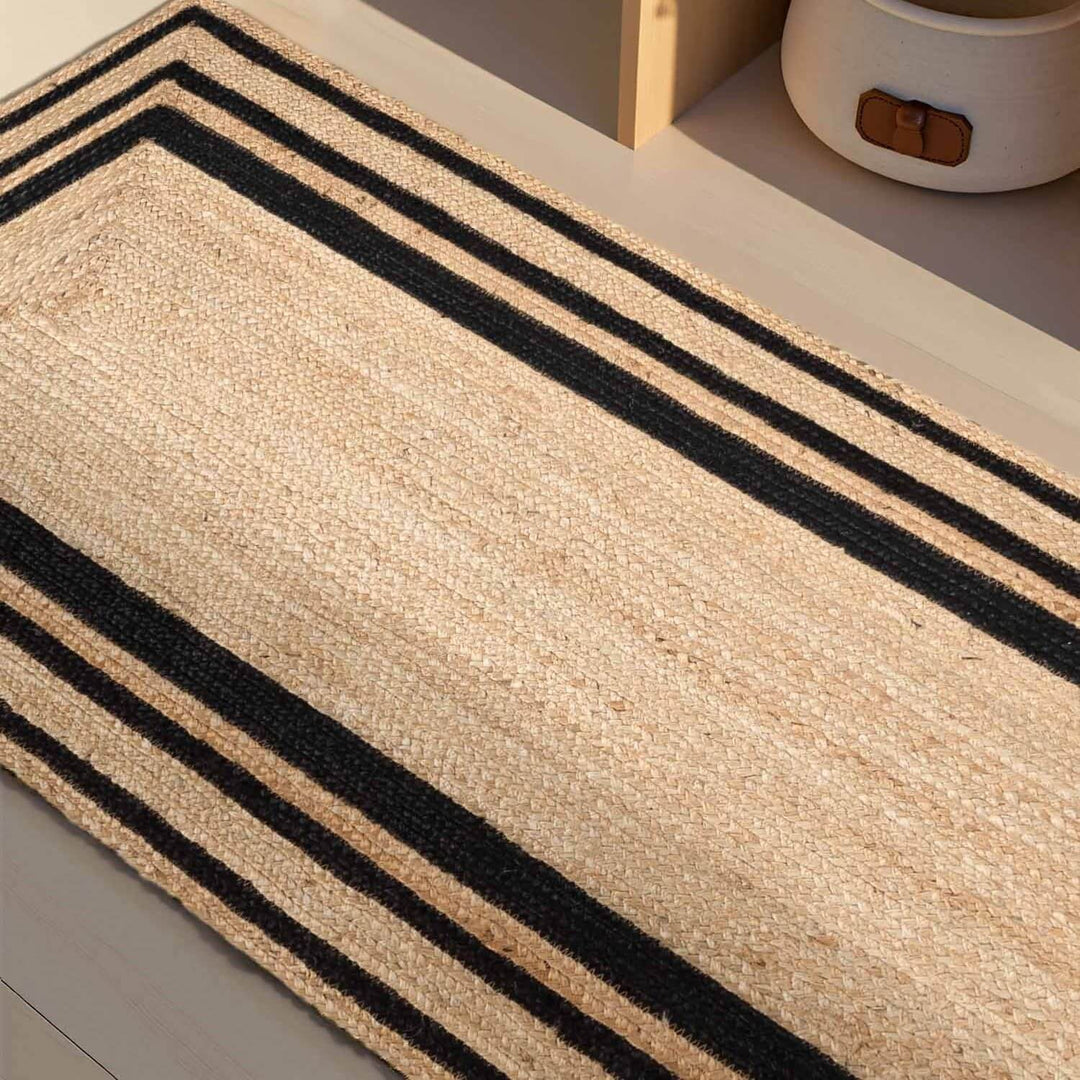Beige rug with black stripes on a light wooden floor.