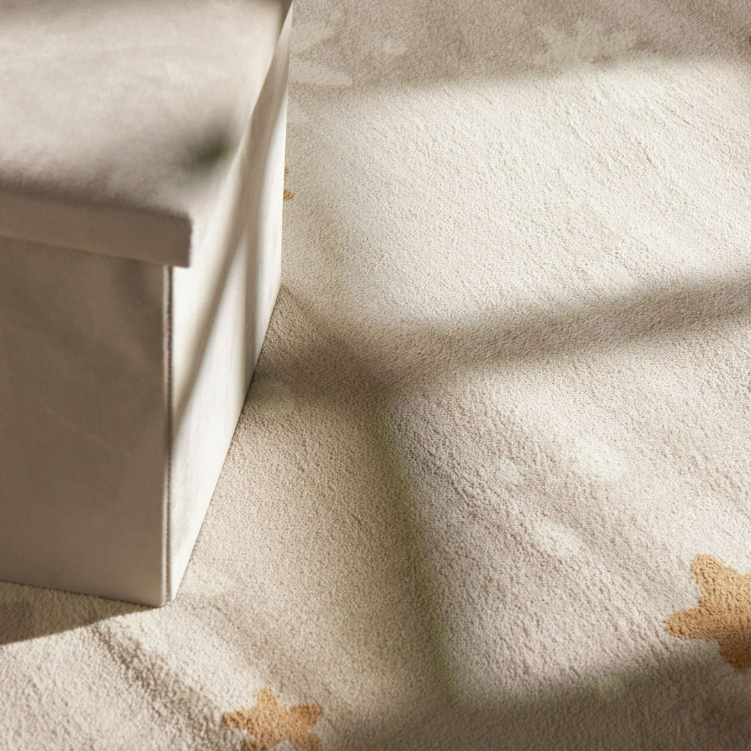 Close-up of a textured beige fabric with star patterns, soft lighting.