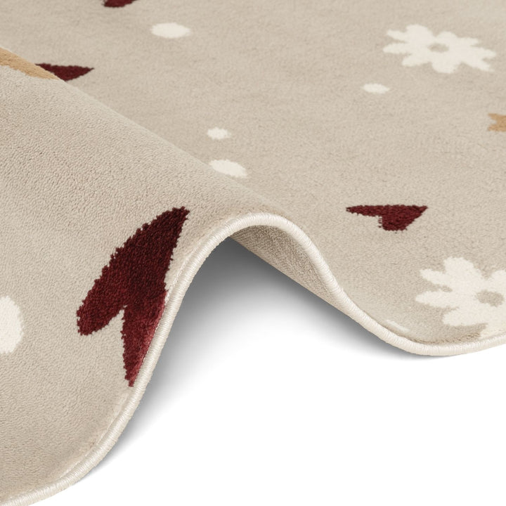 Close-up of a beige rug with red and white floral patterns on a light gray background