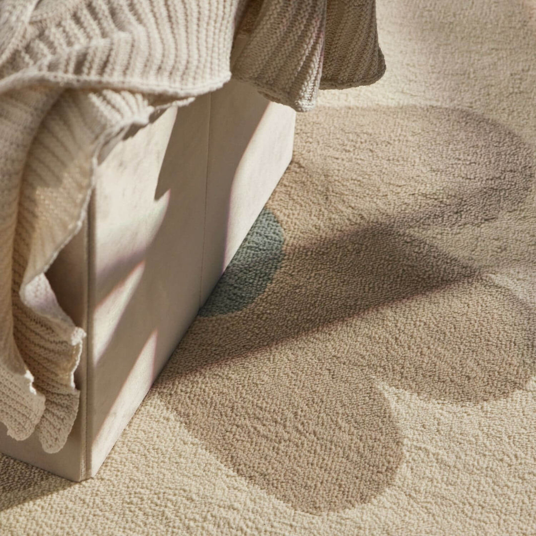 Close-up of a textured beige fabric with a white box and a beige sweater on a matching background.