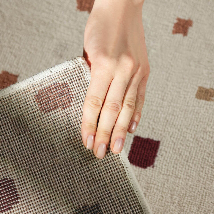 Hand holding a textured fabric with a pattern on a matching fabric background