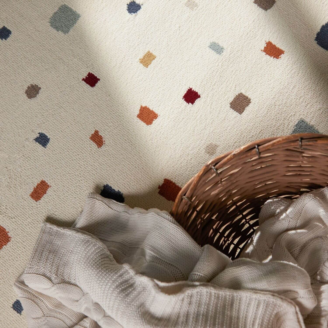 Textured fabric with colorful geometric patterns and a wicker basket on a neutral background