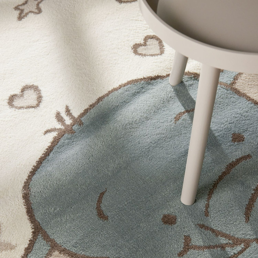 Children's rug with elephant design and heart patterns, partially covered by a white chair.