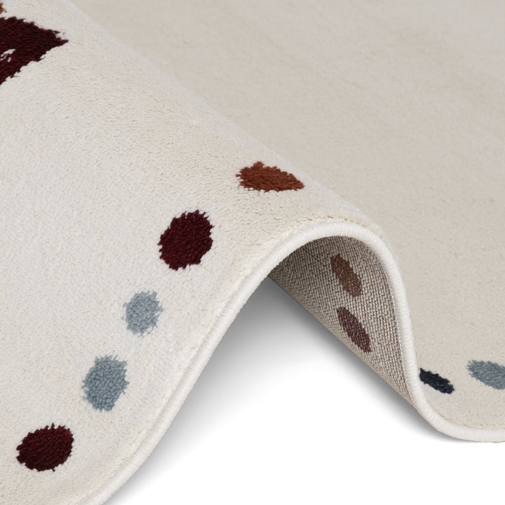 Close-up of a textured fabric with brown and blue polka dots on a beige background